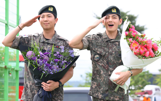 육군 현역 복무를 마치고 만기 전역한 그룹 방탄소년단(BTS) RM과 뷔가 10일 강원 춘천시 신북읍체육공원에서 취재진을 향해 거수경례하고 있다. [연합뉴스]